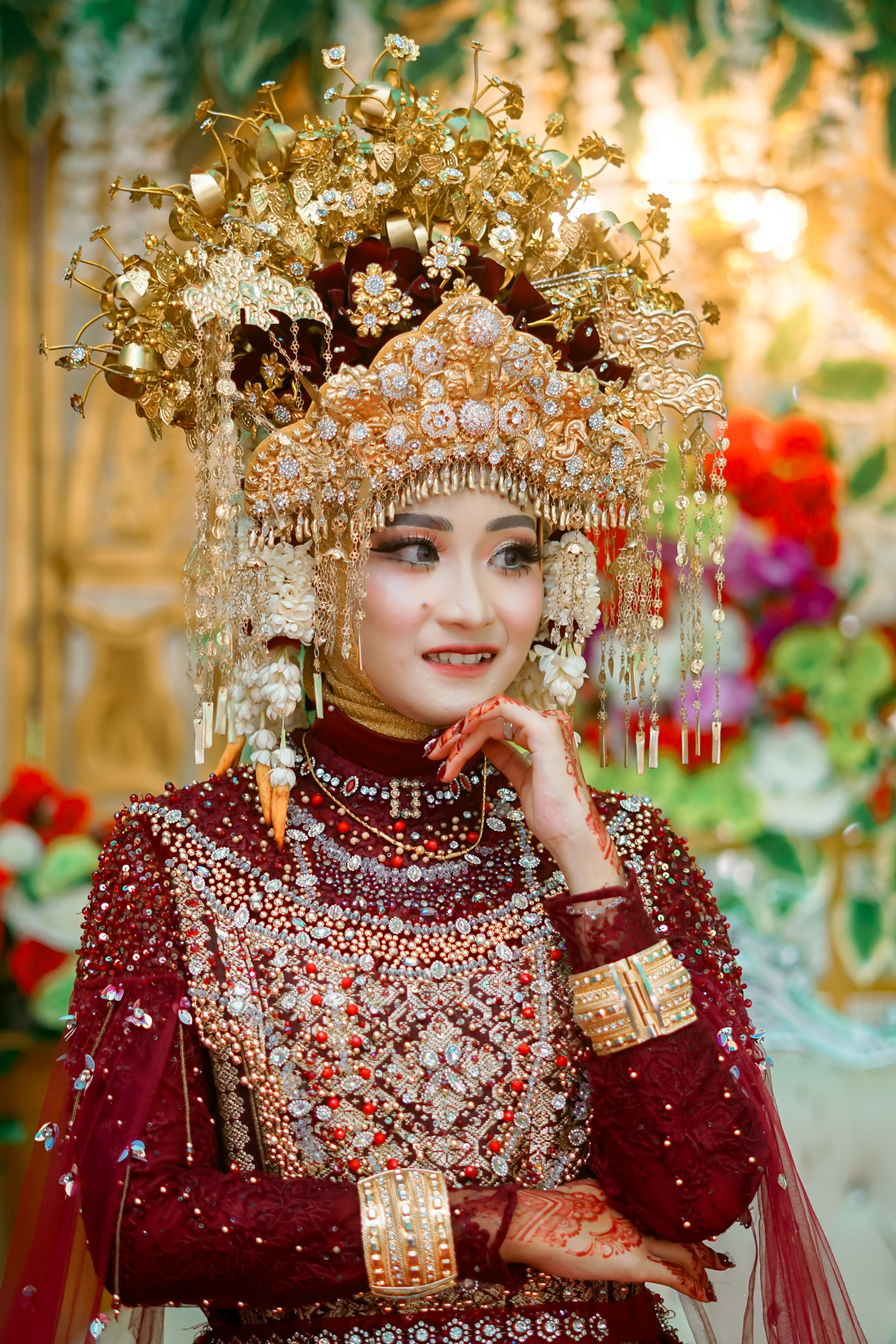 Asian bride in intricate traditional attire, adorned with jewelry and a golden headpiece.