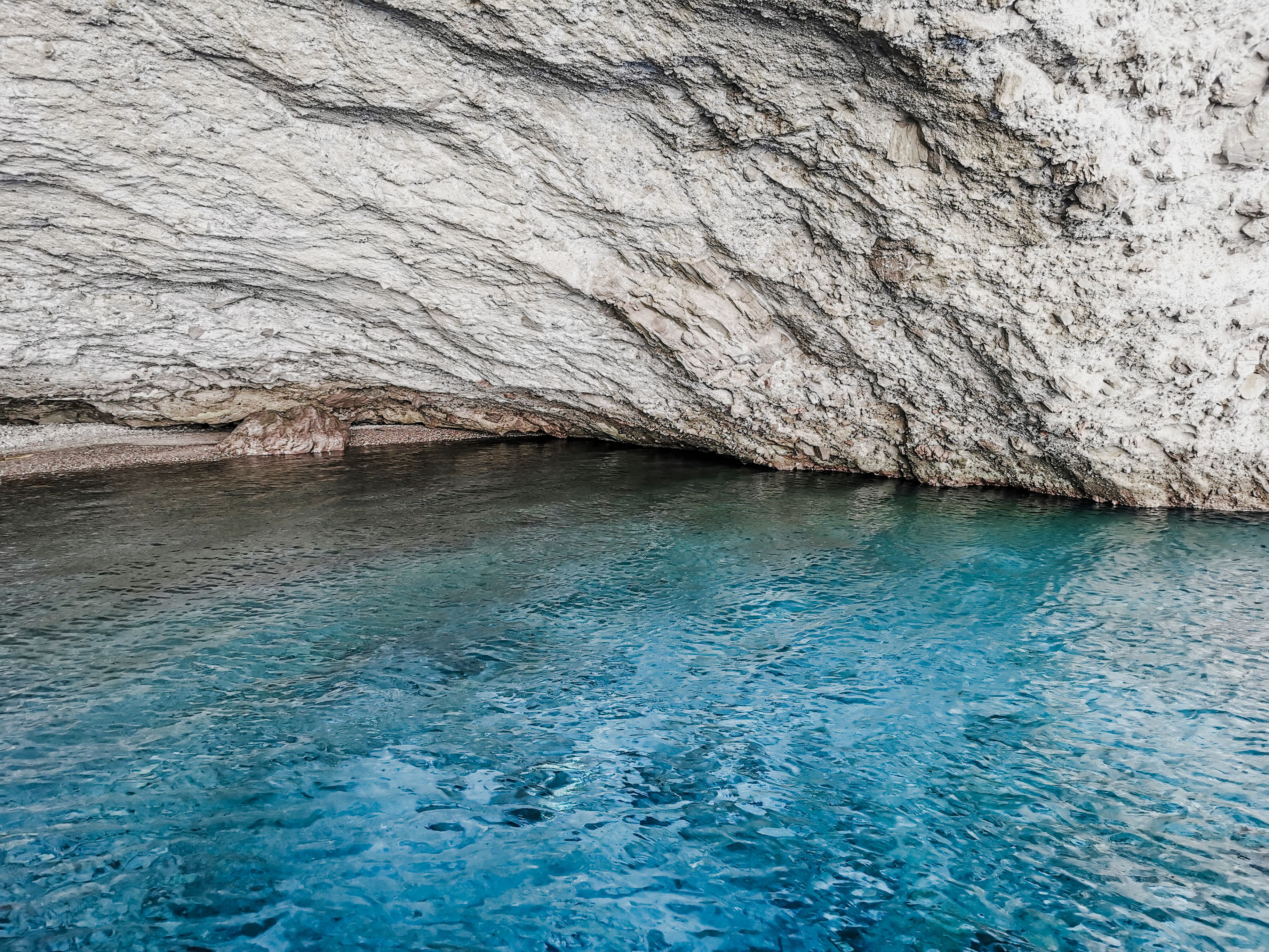 Explore the serene sea cave with turquoise waters and rugged rocky cliffs at Antiparos, Greece. - Photo by Claudia Schmalz on Pexels