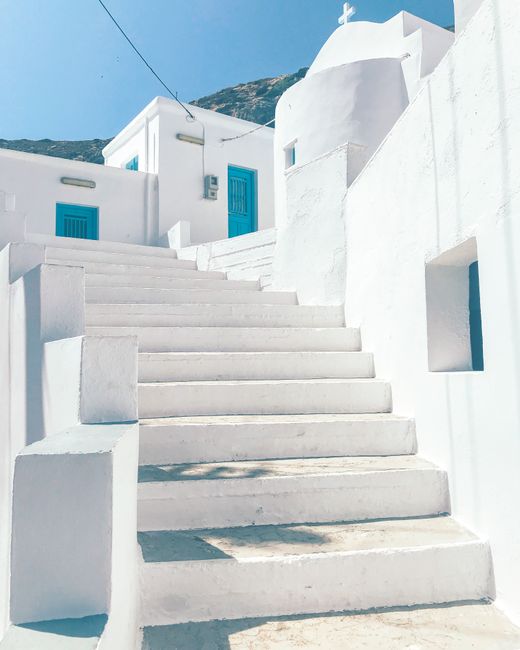 Whitewashed stairs in a traditional Greek town under bright summer sky.