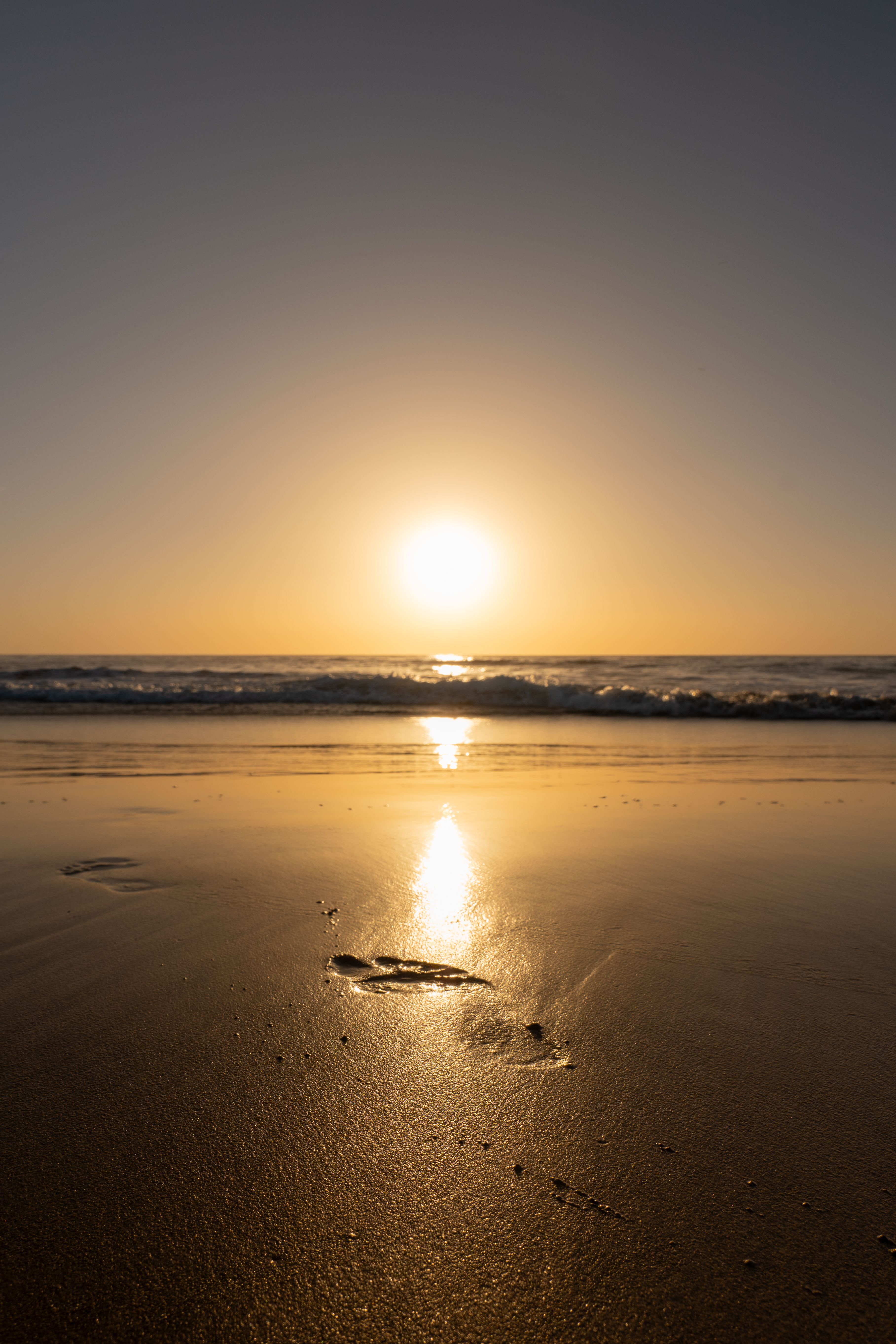 Setting Sun Reflecting in the Wet Sand of the Beach with Footprints ...