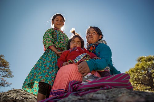 Three women in traditional clothing pose for a photo