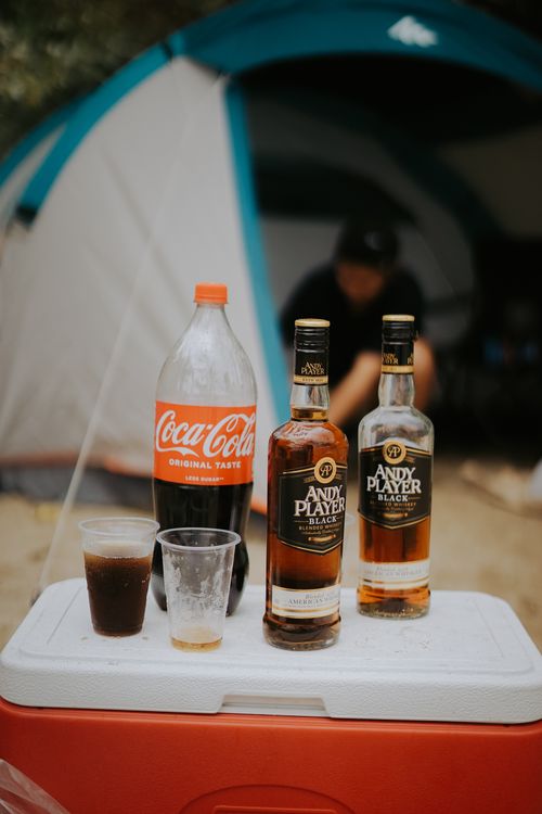 Free Coca-Cola and whiskey bottles on cooler outside a tent. Stock Photo