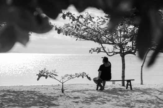 Man Sitting on Bench on Beach in Black and White