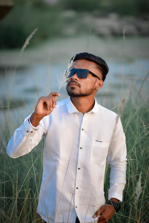 A man in sunglasses and white shirt standing in tall grass