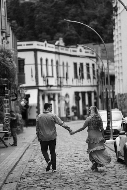 A couple holding hands walking down a cobblestone street