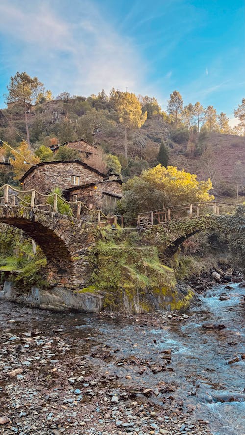 River and Stone Bridges in Village in Autumn