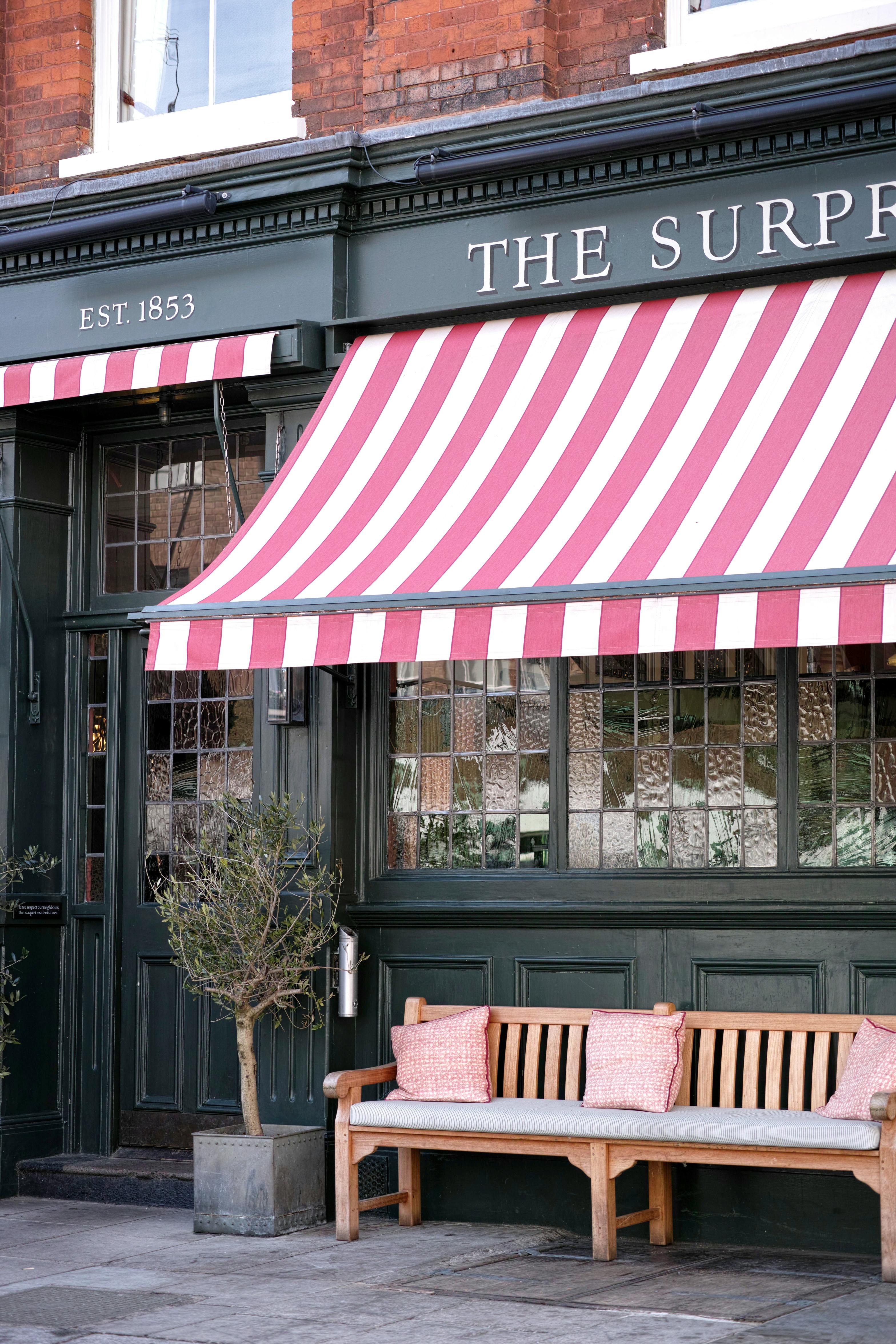 An inviting urban storefront with a striped awning and a wooden bench, perfect for a cozy street scene.