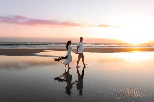 A couple walking on the beach at sunset