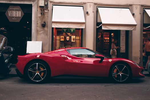 A striking red supercar parked on a vibrant street in Florence, Italy, showcasing urban elegance.