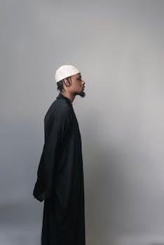 Side profile of a man in a black robe and white cap, embodying minimalist fashion.