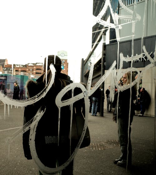 Reflection of Pedestrians and Buildings in a Mirror with Graffiti on a Street
