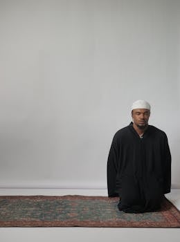 Man in black robe meditating indoors, embracing spirituality and mindfulness.