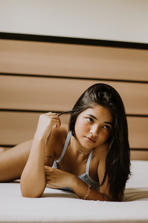 Free Young Woman in Lingerie Posing on a Bed Stock Photo