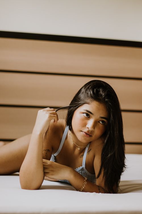 Free A young woman in lingerie posing on a bed in a cozy bedroom setting. Stock Photo