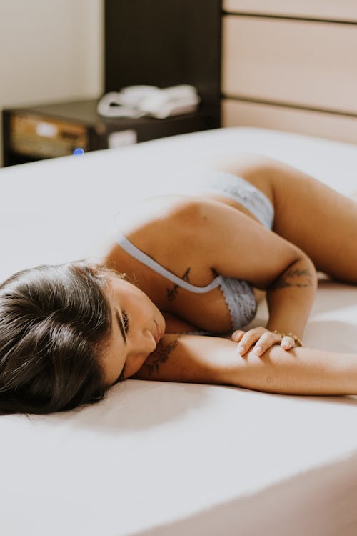 A woman laying on a bed with her legs spread