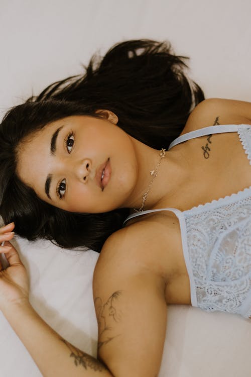 A woman laying on a bed wearing a blue bra