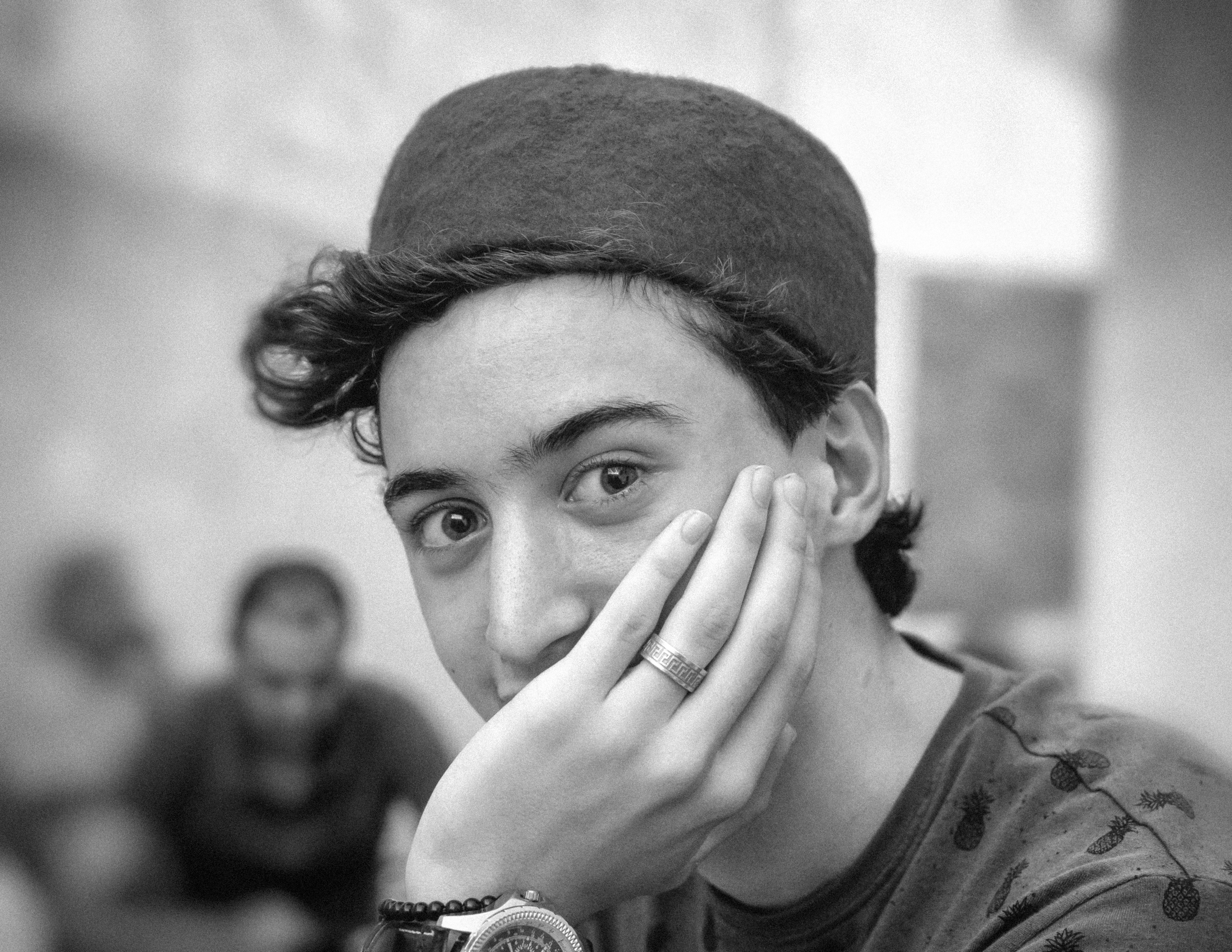 Black and white portrait of a young man in a brimless hat, looking serene.