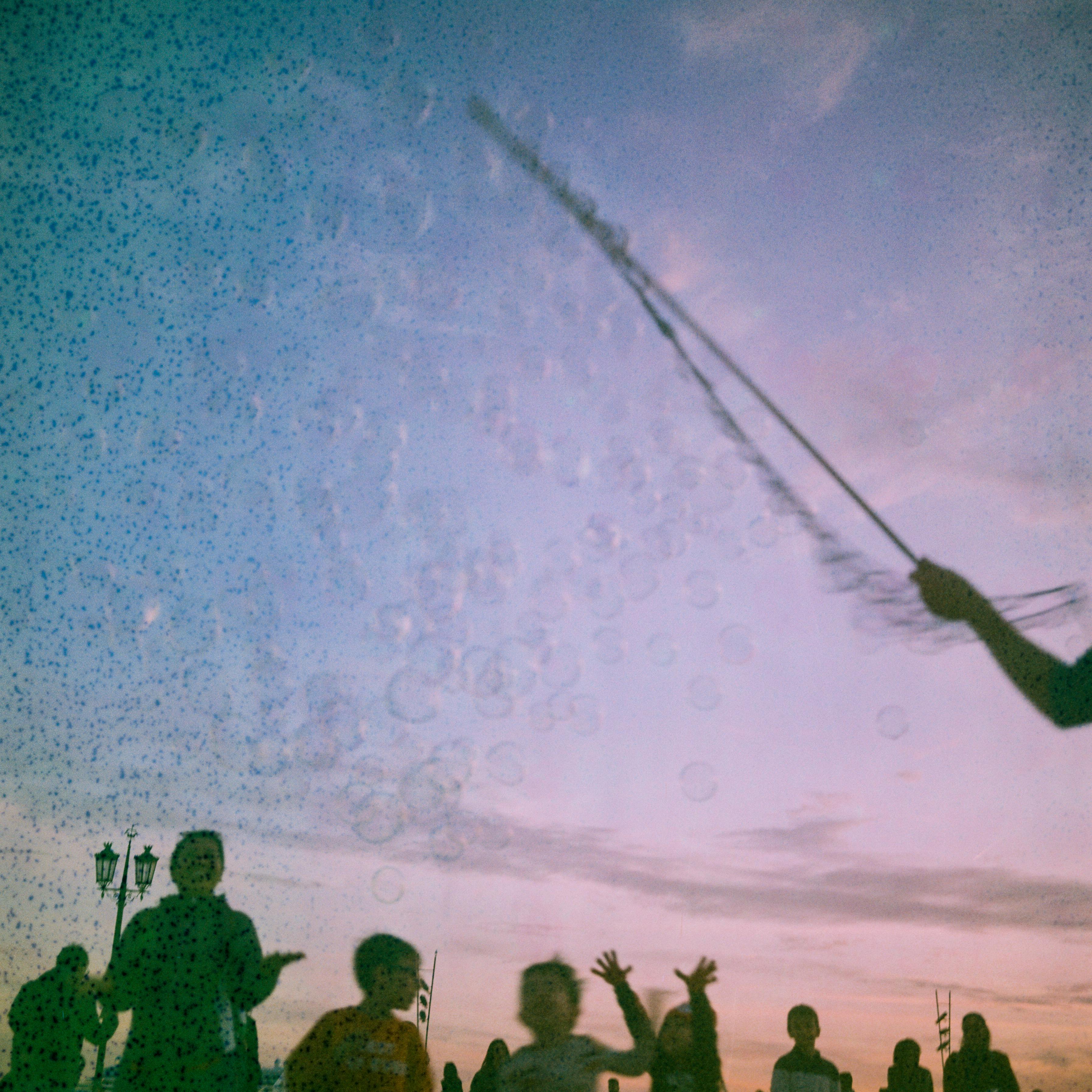 Joyful scene of children playing with bubbles during sunset in Lisbon.