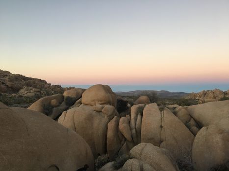 Serene view of rocky desert landscape during twilight with pastel skies.
