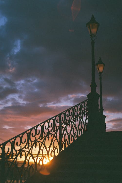 A lamp post and railing at sunset
