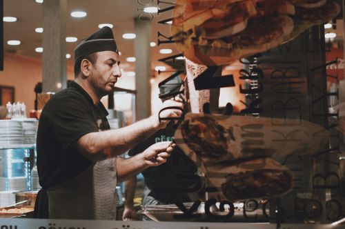 Free A chef in a black uniform prepares a doner kebab in a restaurant kitchen. Stock Photo