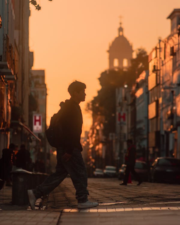 Man Crossing Street in City at Sunset