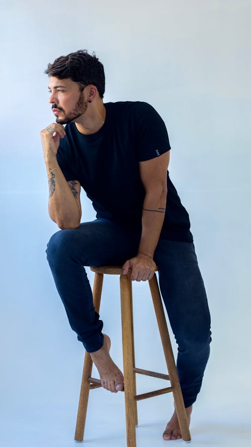 Handsome Man in Black T-Shirt Sitting on Wooden Stool