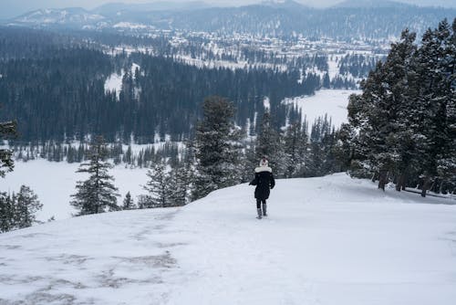 A person walking down a snowy hill in the mountains