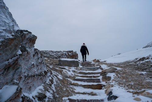 A man walking up a snowy hill with steps