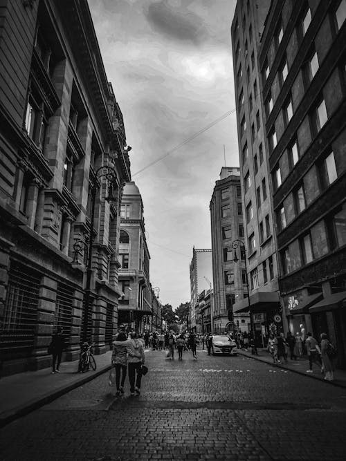 People Walking on Cobblestone Street in Black and White