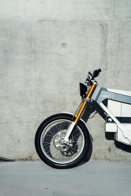 A white and yellow motorcycle parked against a concrete wall