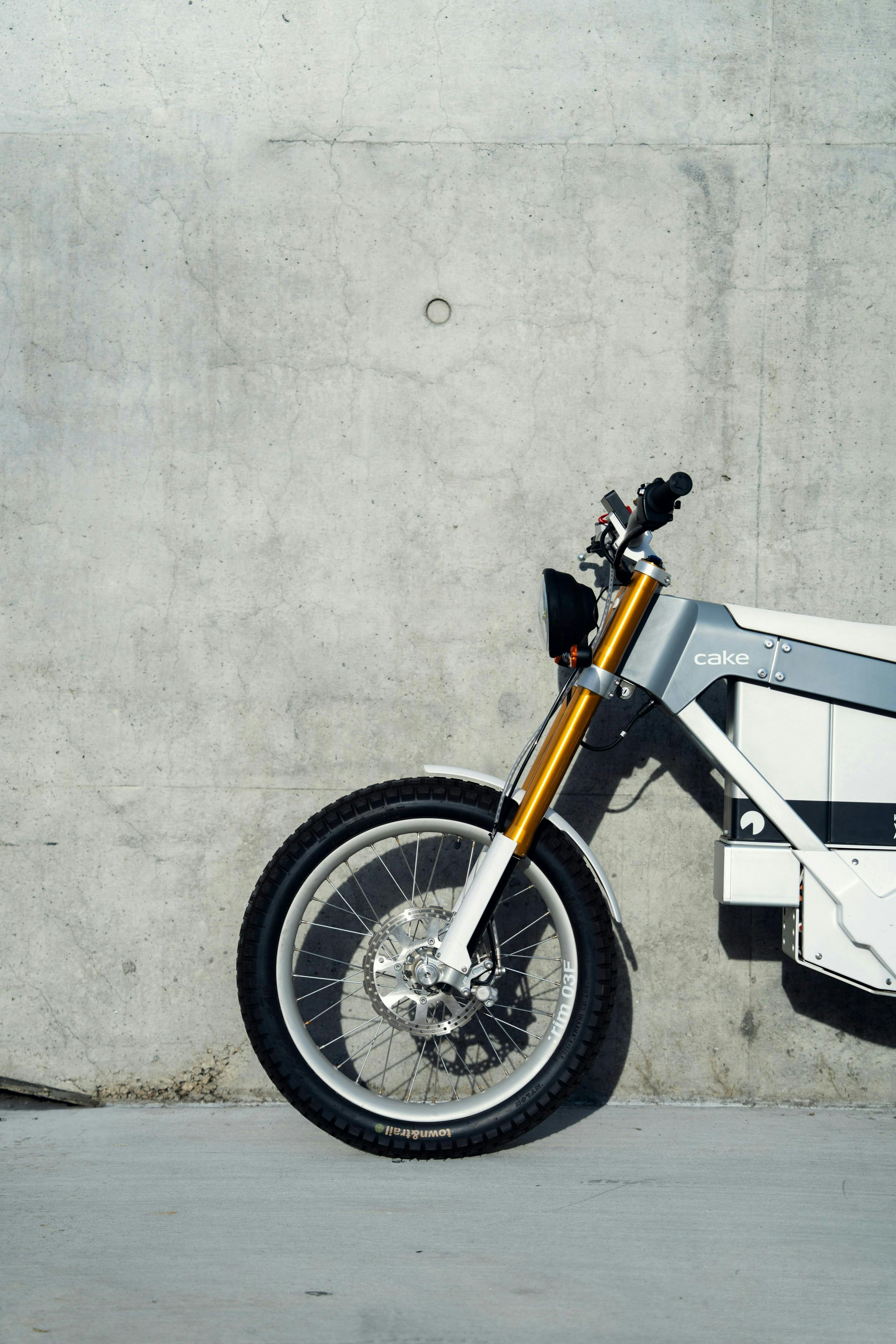 Free A white and yellow motorcycle parked against a concrete wall Stock Photo