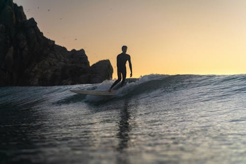 A surfer rides a wave at sunset