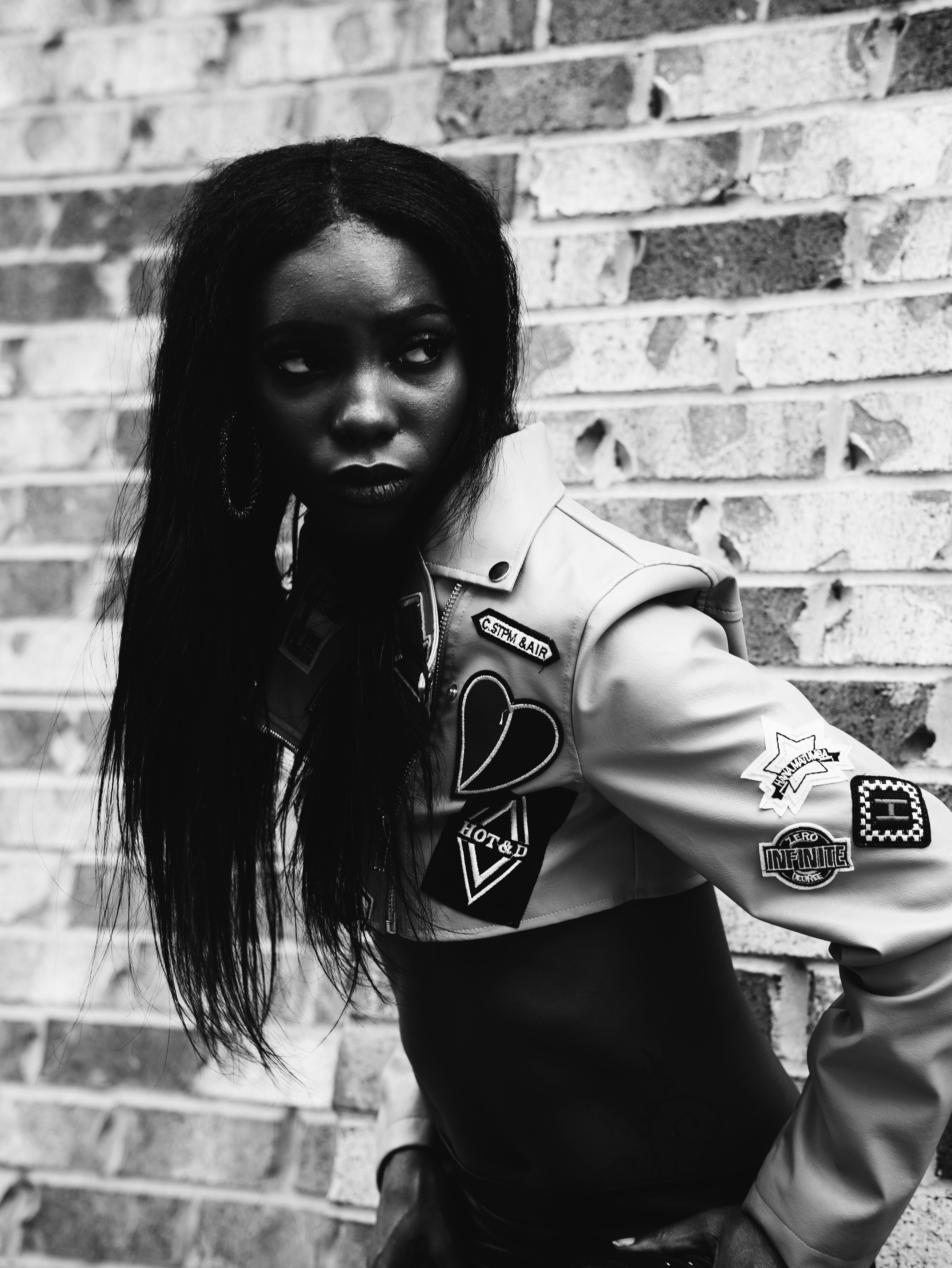 Black and white portrait of a woman in fashion jacket against a brick wall in Atlanta.