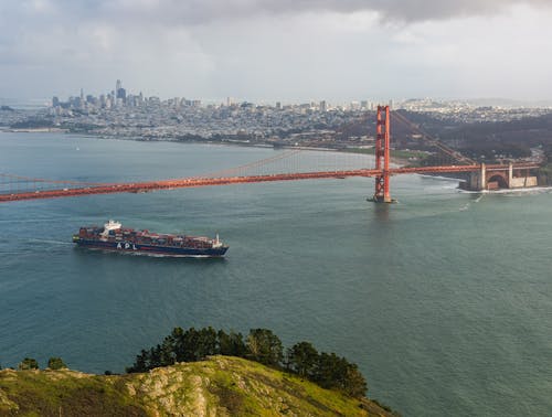 A ship is traveling under the golden gate bridge