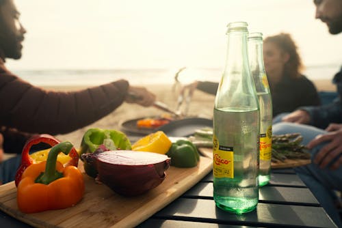 Bottle and Vegetables on Table on Beach