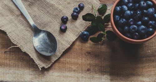 Blueberries on Mug and Brown Surface Near Spoon