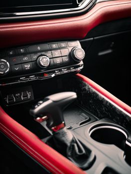Close-up of a luxury car's interior showcasing modern controls and red leather trims.