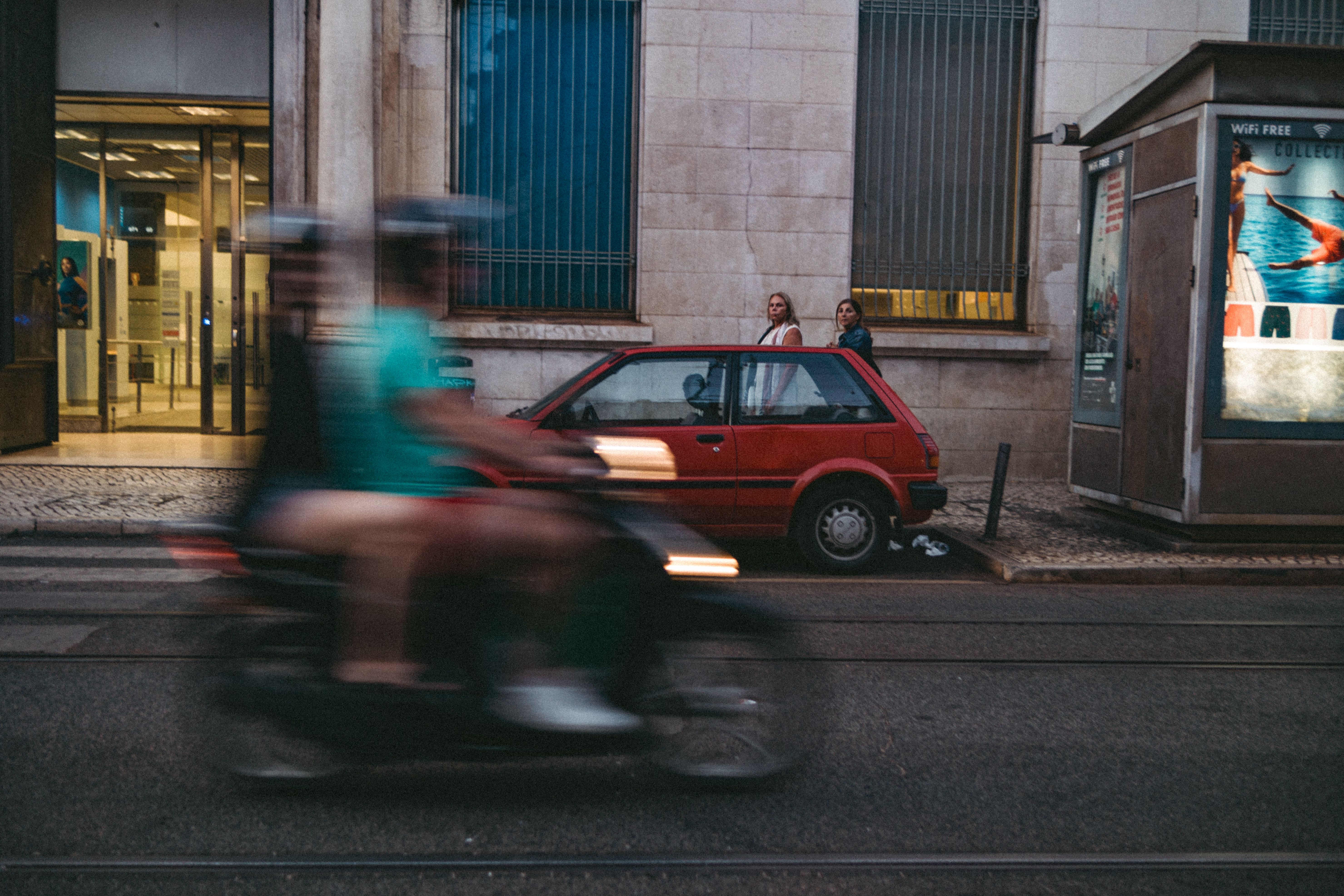 Street view in Lisbon capturing motion blur of motor scooter passing by.