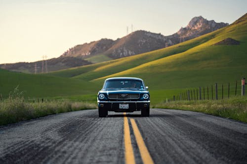 A classic car driving down a road in the mountains