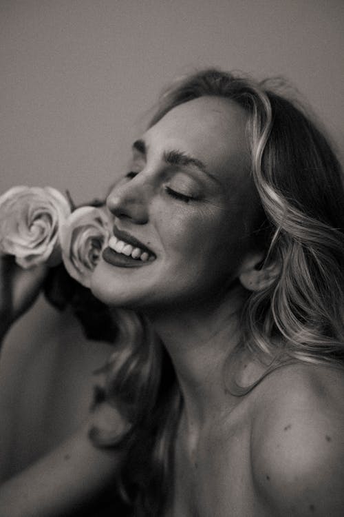 A woman is smiling while holding a rose