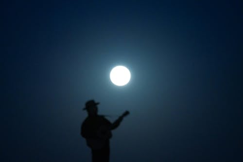 A man playing guitar in the moonlight