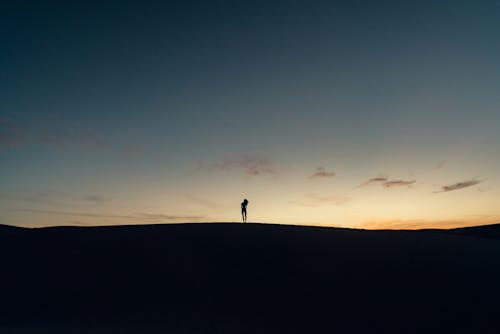 A person standing on top of a hill at sunset