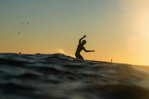 A surfer is riding a wave at sunset