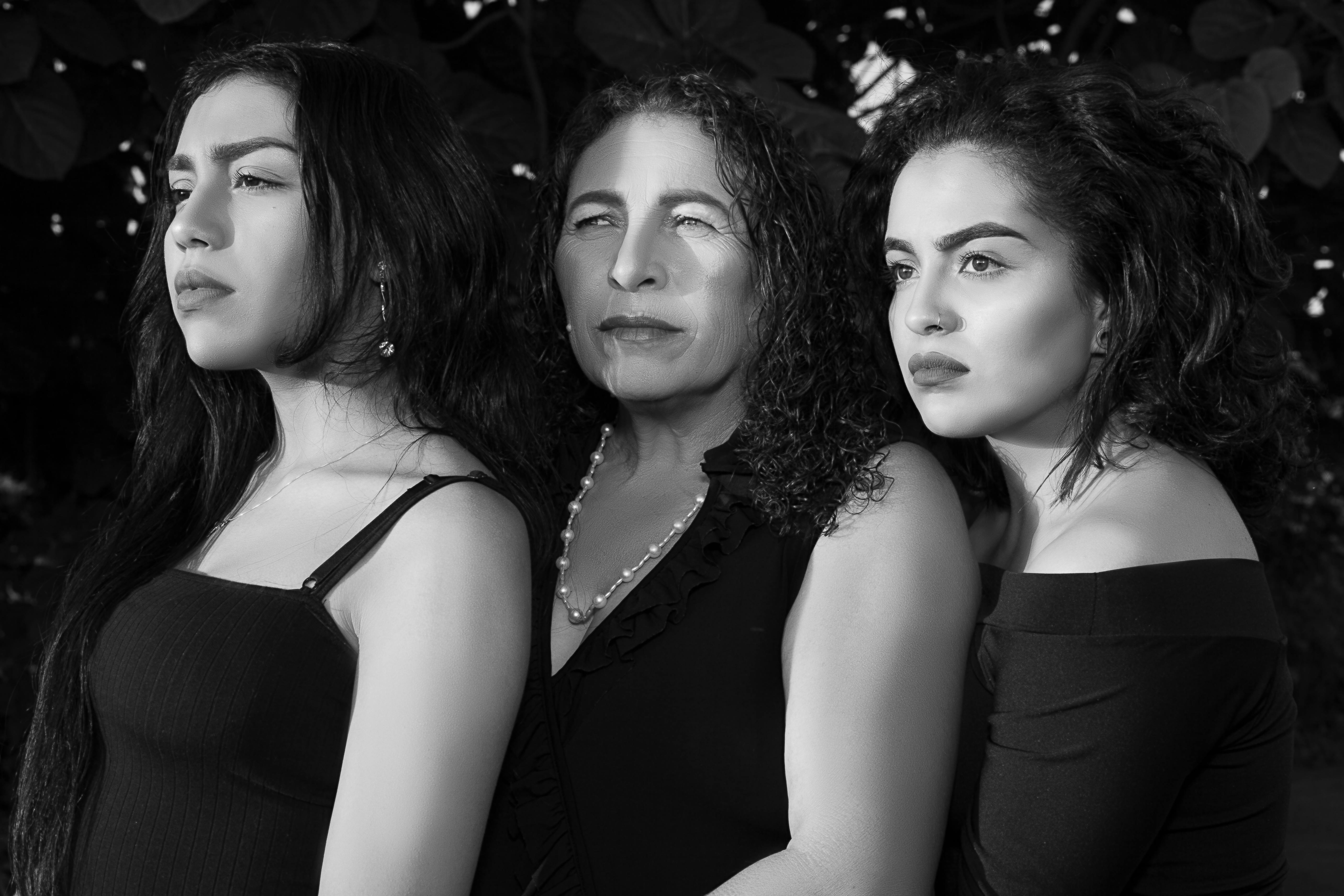 A sophisticated black and white portrait capturing the elegance and unity of three women.