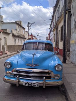 Classic blue Chevrolet car parked on a charming Cuban street with vintage architecture.