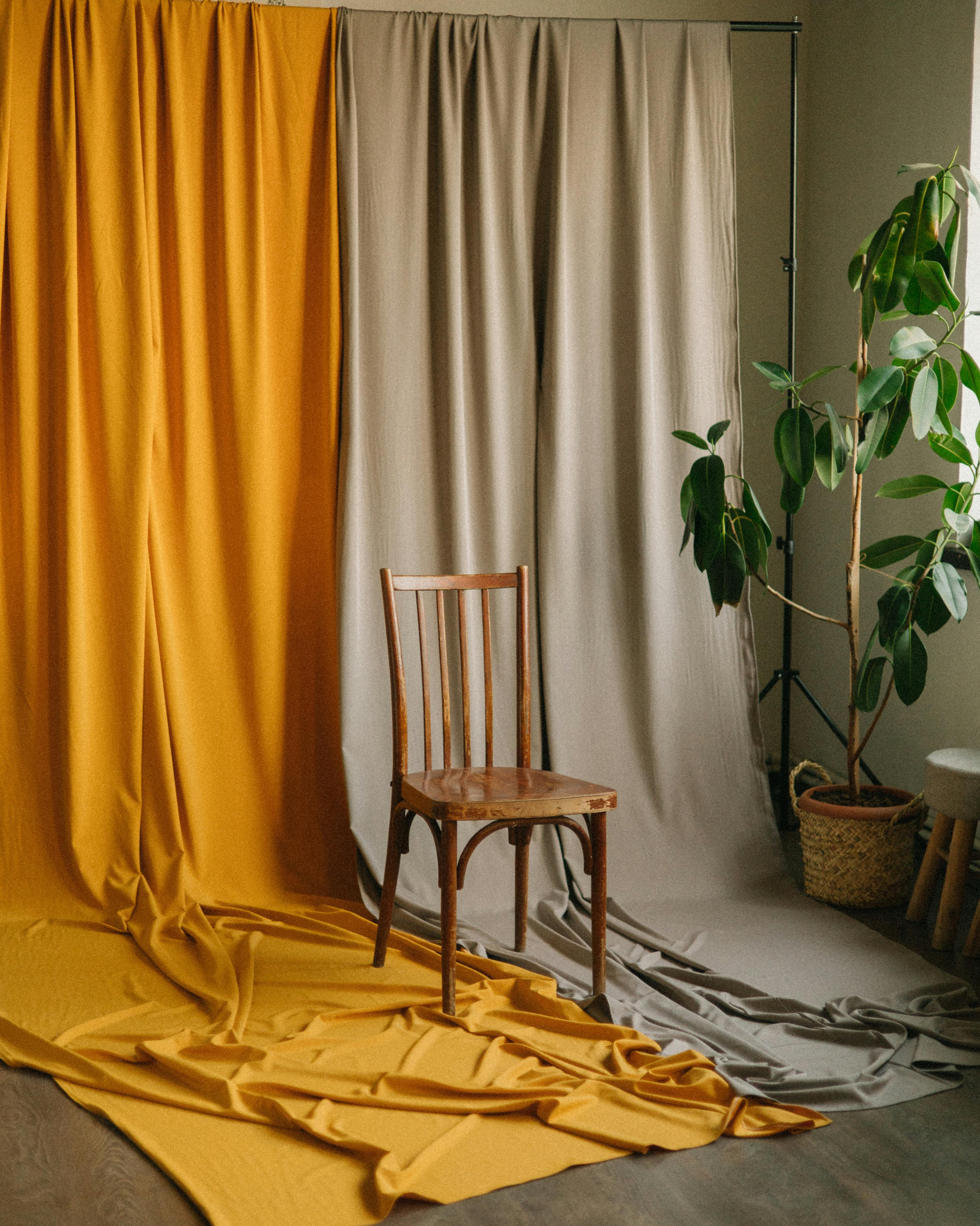 Wooden chair against colorful drapes in an indoor setting, perfect for minimalist interiors.