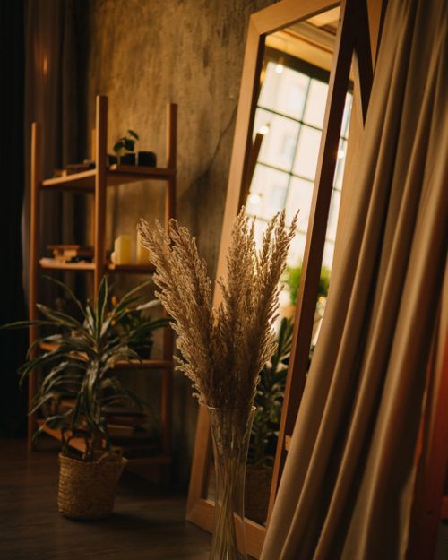 Free Warm interior with plants, wooden furniture, and decorative mirror in a cozy room. Stock Photo