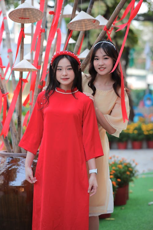 Two asian women in red dresses standing next to each other