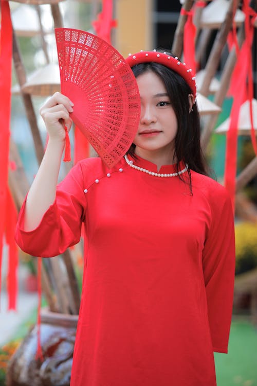 A woman in red holding a fan